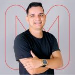 Foto do diretor Marlos Morbis, com o "N" de NextAge ao fundo