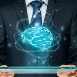 Homem de negócios segurando um tablet com um holograma de um cérebro, simbolizando inteligência artificial e inovação tecnológica.