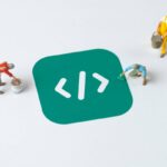 Miniaturas de trabalhadores pintando um ícone de programação em um conceito criativo de desenvolvimento de software low-code