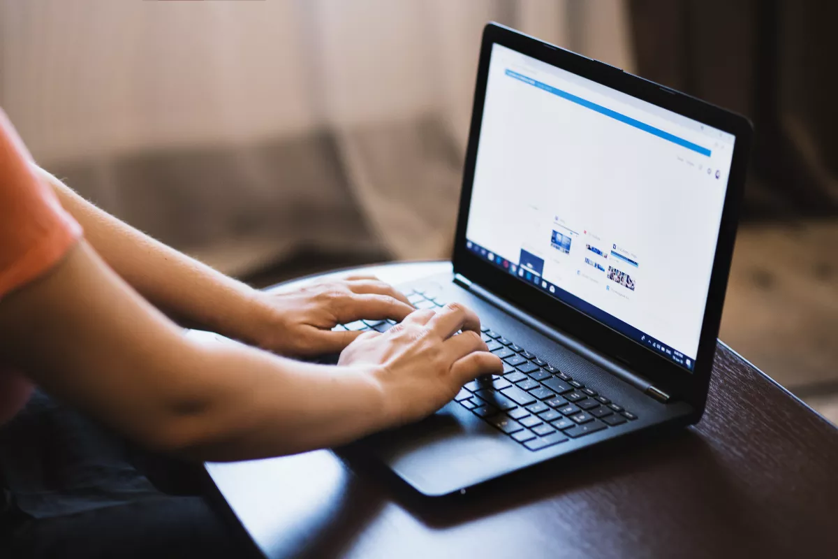 Mão digitando em um teclado de computador, representando trabalho, tecnologia e produtividade.