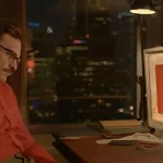Homem sentado na frente de um computador.