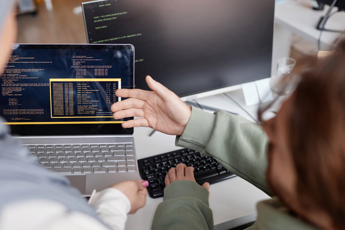 Two developers analyzing and reviewing code together on a computer screen, collaborating on a code review.