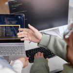 Dois desenvolvedores analisando e revisando código juntos na tela do computador, colaborando em um code review.