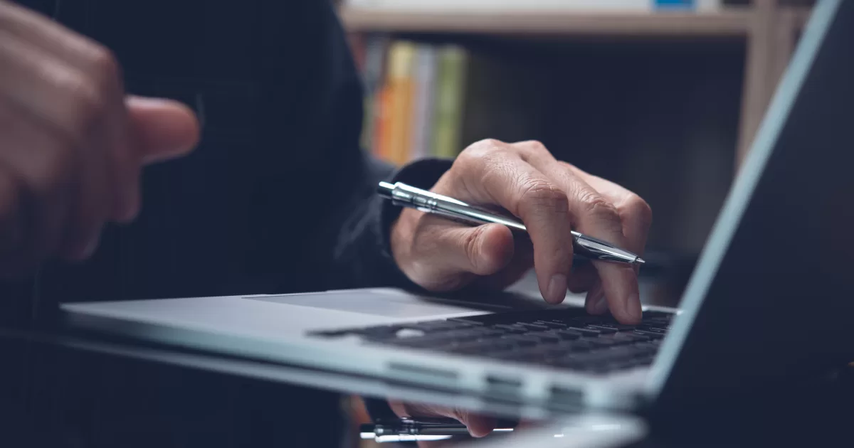 Imagem de mão digitando no computador segurando um lápis representando lifelong learning