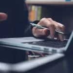 Imagem de mão digitando no computador segurando um lápis representando lifelong learning