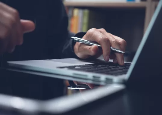 Imagem de mão digitando no computador segurando um lápis representando lifelong learning