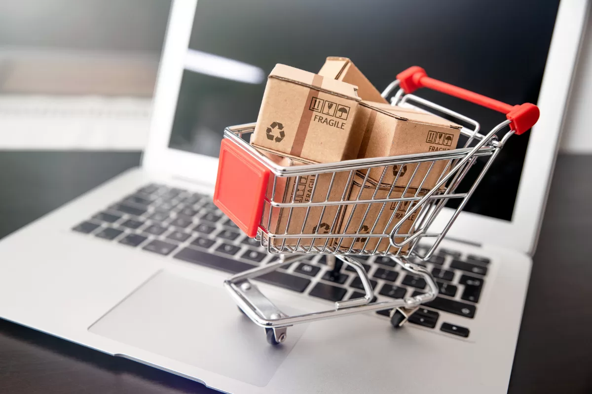 A shopping cart above a laptop representing staff augmentation for e-commerce 