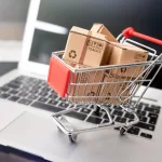 Imagem de um carrinho de compras em cima de um notebook representando outsourcing para e-commerce