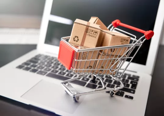 Imagem de um carrinho de compras em cima de um notebook representando outsourcing para e-commerce
