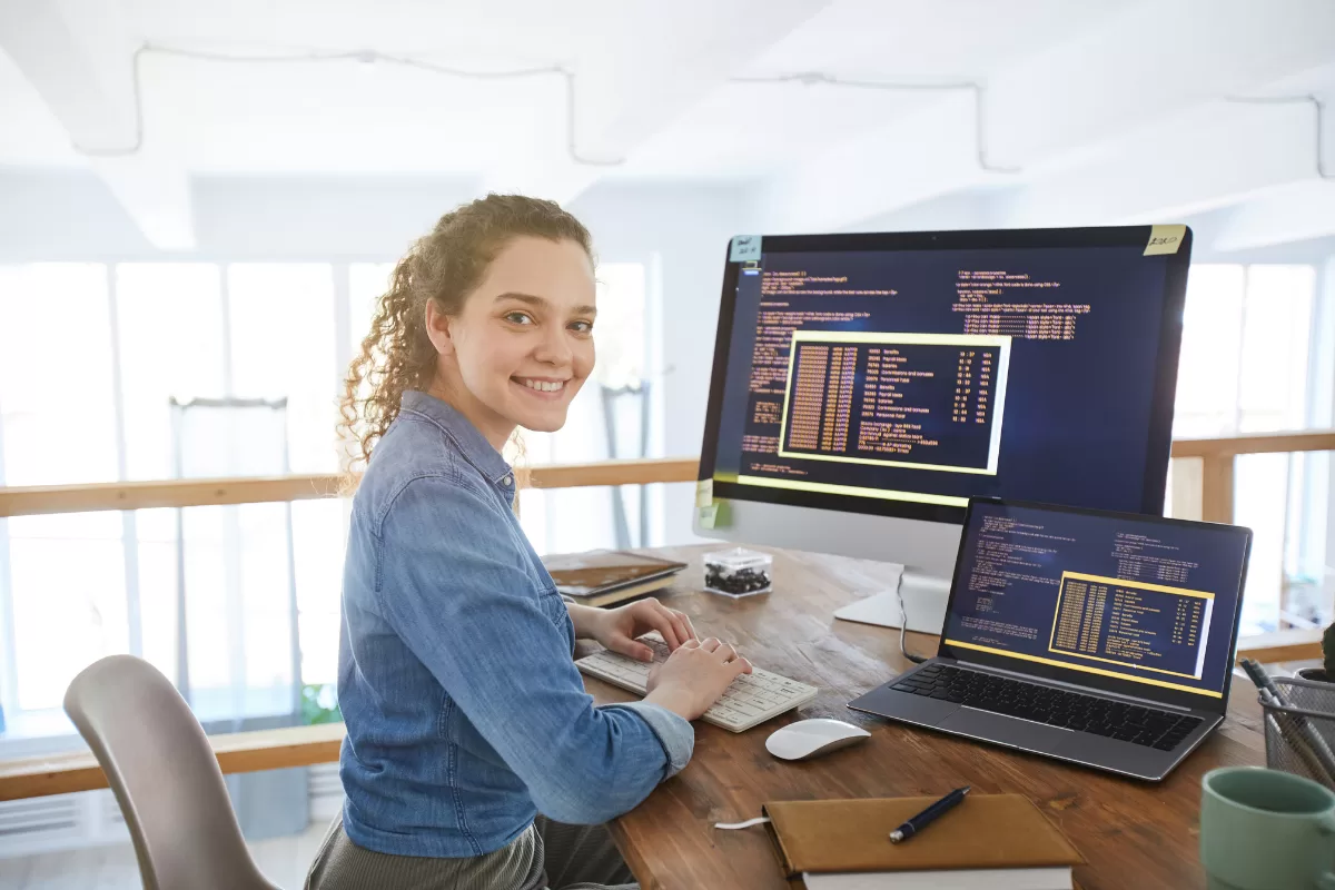 Imagem de uma mulher loira na frente de um computador trabalhando em uma fábrica de software