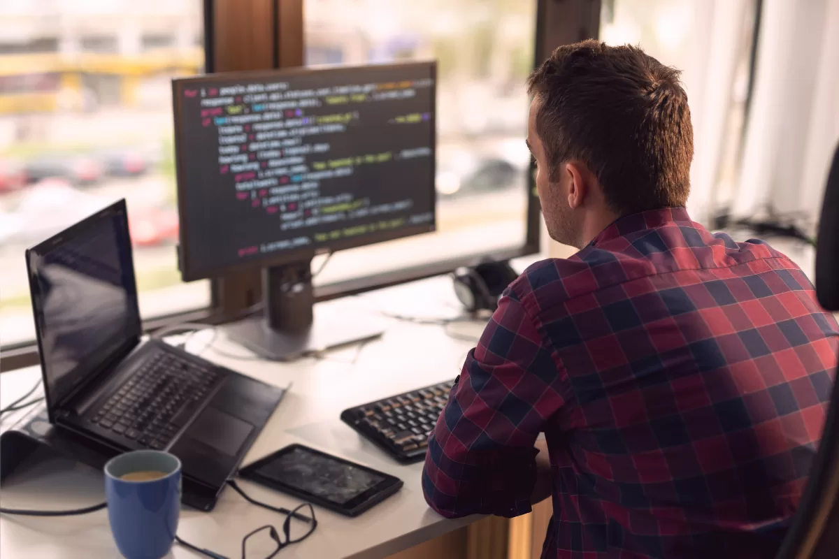 Um homem escrevendo códigos na frente do computador