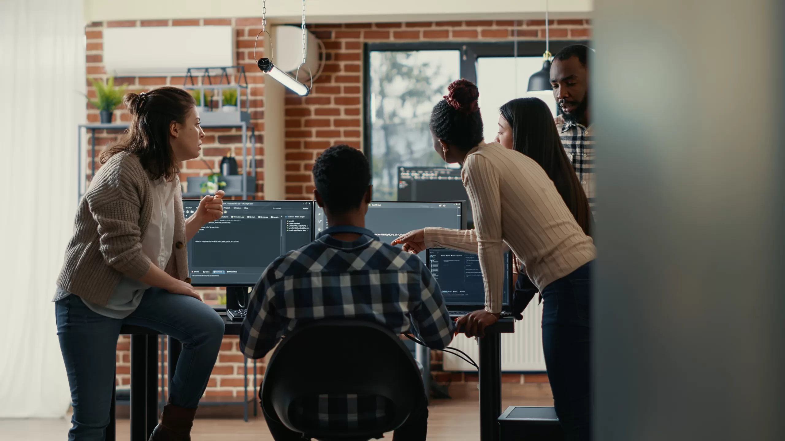 Equipe de desenvolvimento discutindo um trecho de código na tela, com programadores concentrados em um ambiente de escritório moderno e colaborativo.