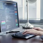 Profissional programando em um notebook com editor de código aberto, trabalhando em um escritório com decoração industrial.