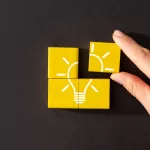Quatro blocos amarelos formando uma lâmpada, representando inovação, ideias criativas e soluções estratégicas para empresas, representando o processo de validar projetos