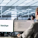 Desenvolvedor em escritório moderno trabalhando com dois monitores, um exibindo a logo da NextAge com o slogan 'More than code. People.' e outro mostrando código de programação, representando frameworks 2026