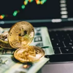 Moedas de bitcoin douradas sobre notas de euro em teclado de laptop com gráficos financeiros desfocados ao fundo na tela