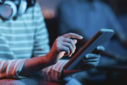 Desenvolvedor trabalhando em laptop com código de programação na tela em ambiente de desenvolvimento integrado (IDE) com iluminação azul ao fundo representando tendências da tecnologia