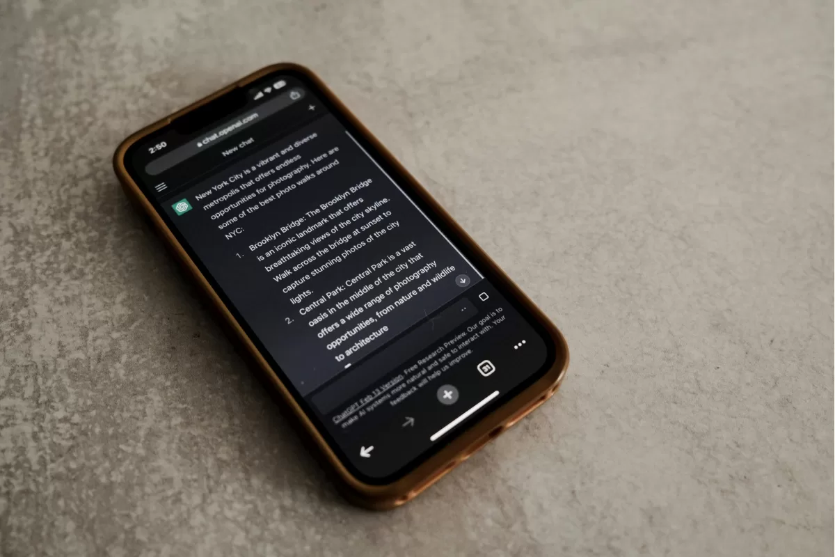Celular exibindo uma conversa com inteligência artificial em uma interface escura, apoiado sobre uma superfície clara.
