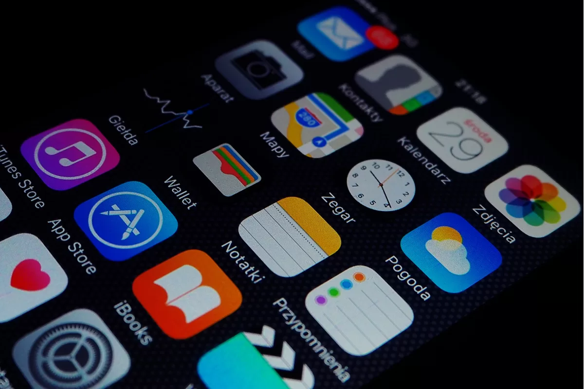 Smartphone screen displaying various organized apps, including App Store, Wallet, Mapy and other mobile interface icons on dark background