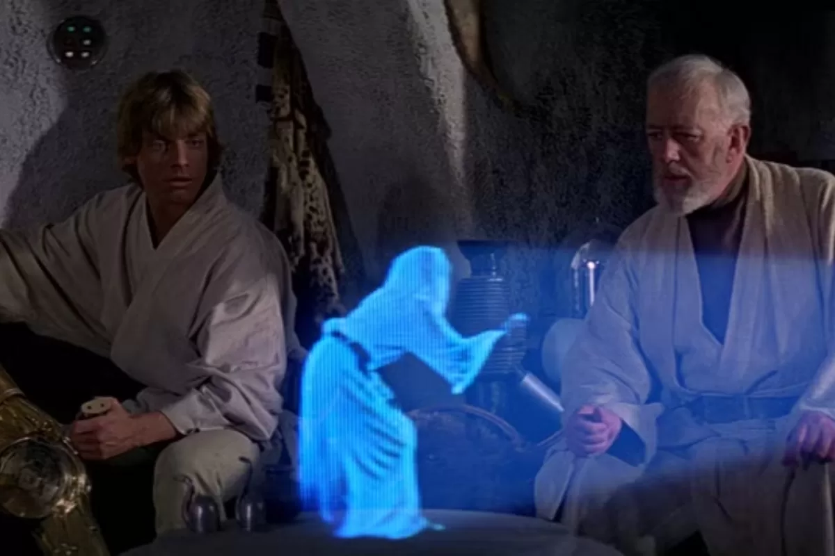 Luke Skywalker e Obi-Wan Kenobi assistem à projeção de um holograma azul da Princesa Leia em Star Wars.