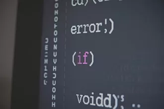 Close-up em uma tela de computador exibindo linhas de código de programação em uma interface de desenvolvimento escura. O texto mostra termos como "error", "if" e "void" com destaque em cores diferentes.