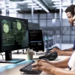 Equipe de desenvolvedores trabalhando em múltiplos monitores com código de segurança e análise de vulnerabilidades em ambiente de desenvolvimento