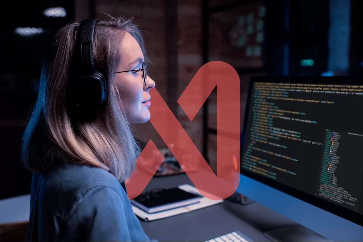 Tech professional wearing headphones analyzing code on a monitor in a dark, blue-lit environment.