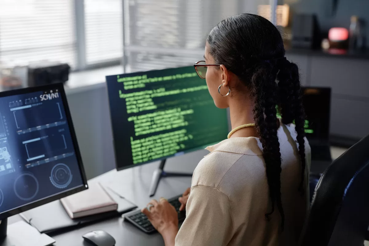 Software engineer working on code with dual monitors in modern office