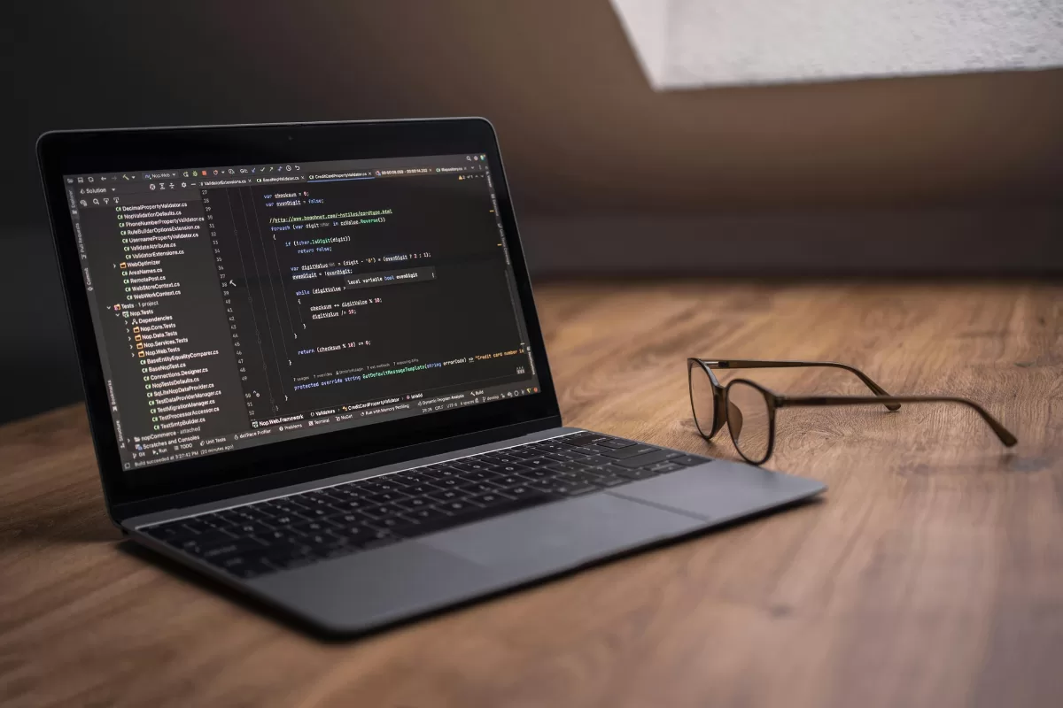 Laptop aberto exibindo código de programação em editor de desenvolvimento, ilustrando as habilidades técnicas essenciais de um desenvolvedor full stack