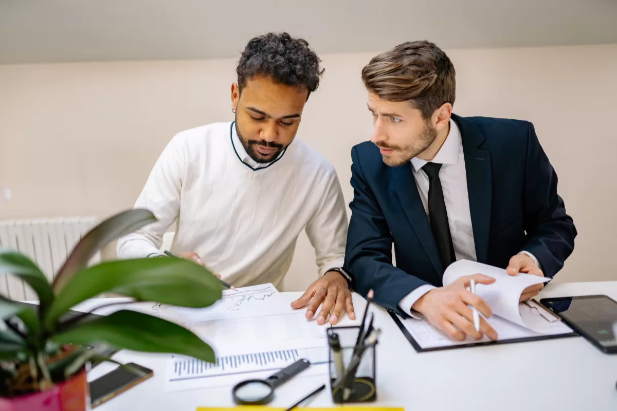 Gestor de TI em reunião estratégica com profissional de outsourcing, analisando documentos e planejando alocação de equipe de desenvolvimento