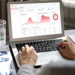 Pessoa mexendo no laptop com a tela dos gráficos do NextFlow AI, serviço da NextAge.