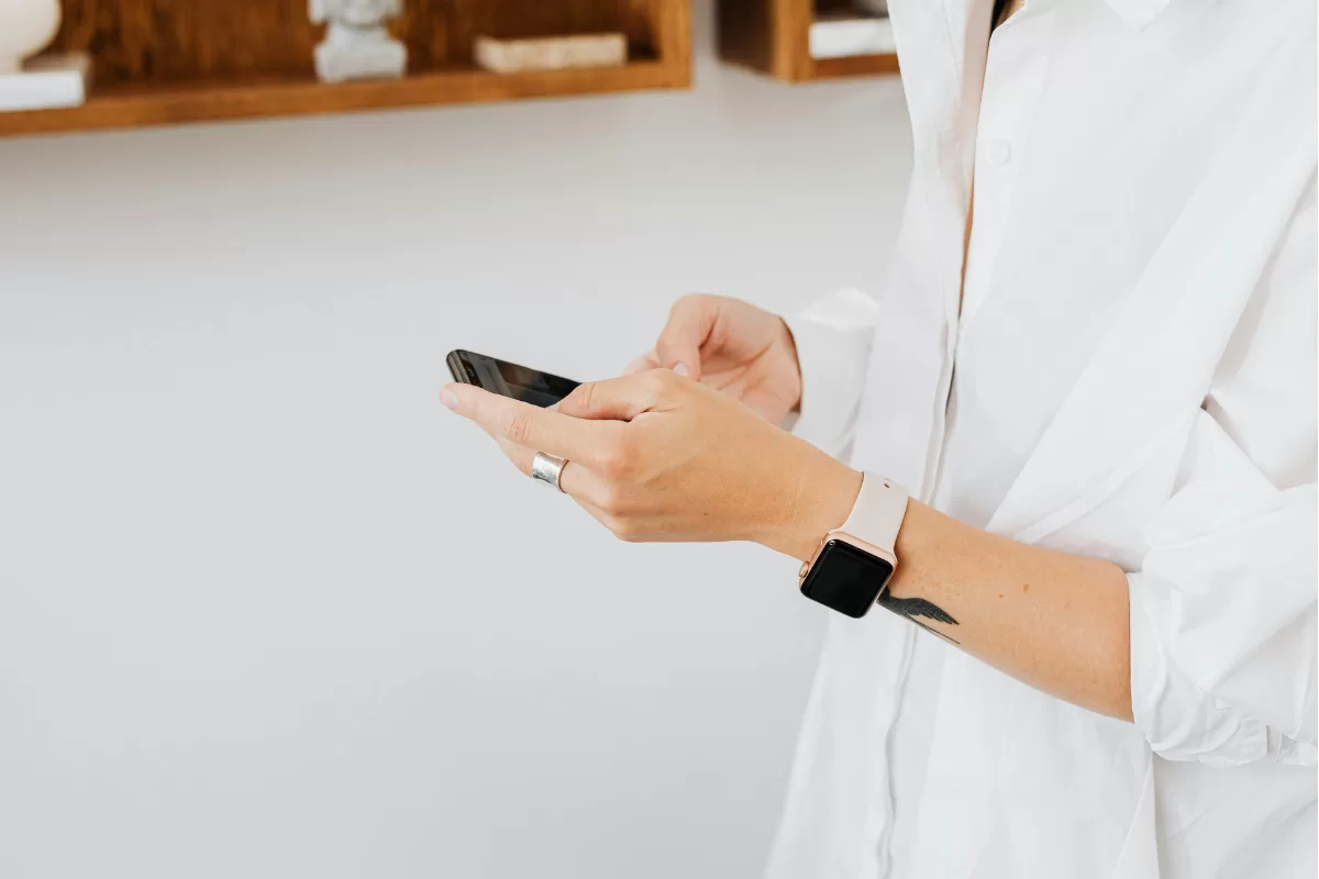 Person holding a smartphone while wearing an Apple Watch, illustrating everyday mobile device usage