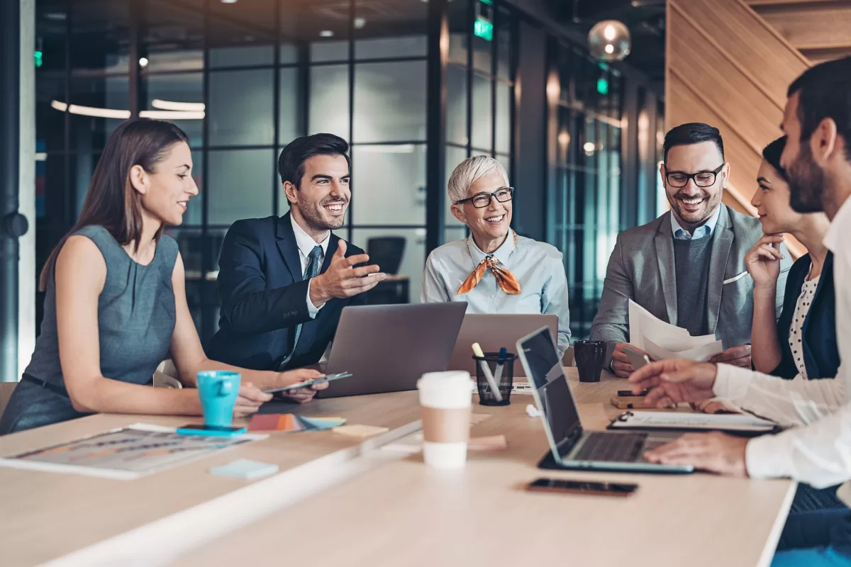 Three technology professionals collaborating in front of a monitor, representing a development team working under an IT outsourcing model