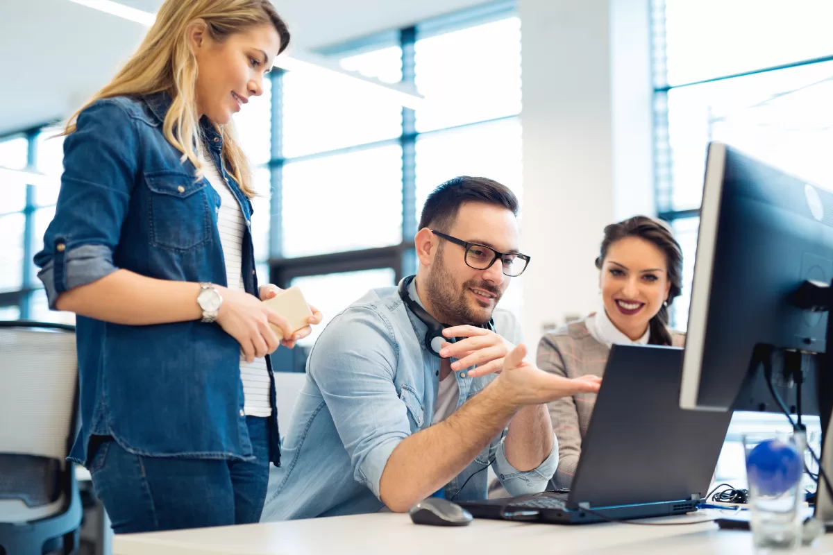 Team of professionals in a work meeting around a table with laptops, representing collaboration between teams in an outsourcing model