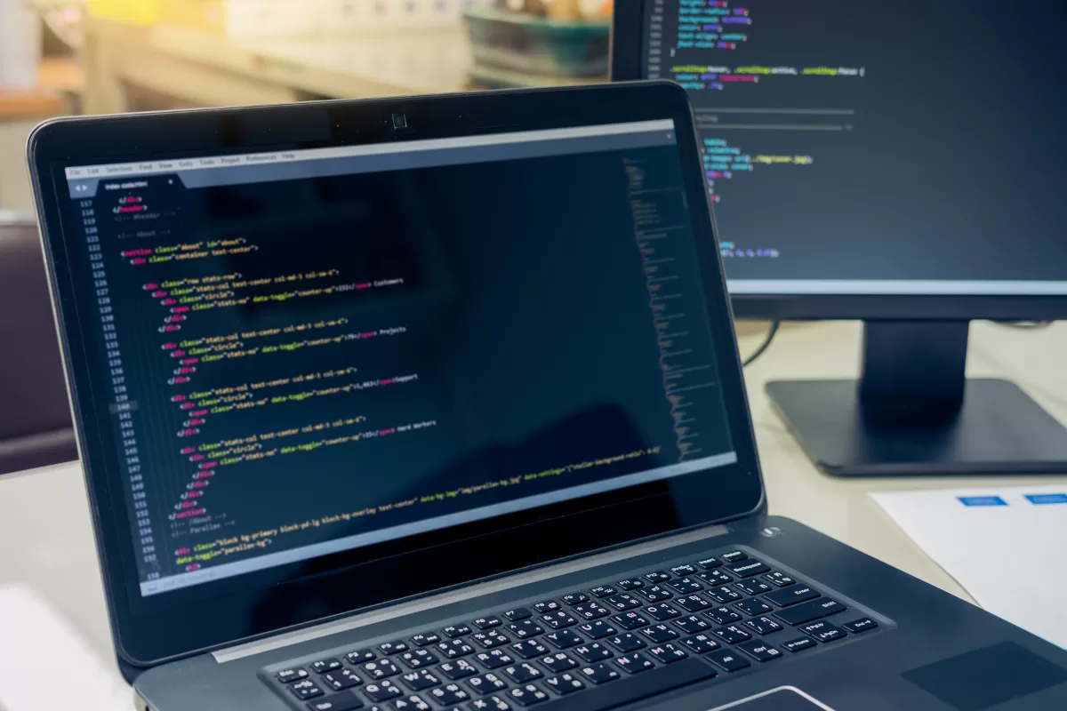 Laptop with a code editor open displaying colorful HTML and CSS, representing software development