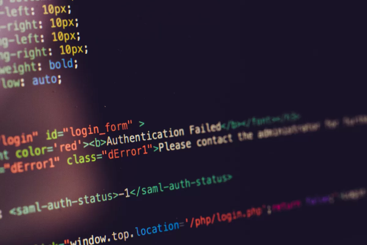 Close-up of a dark screen showing colorful HTML and PHP code, highlighting authentication snippets and a login form structure.