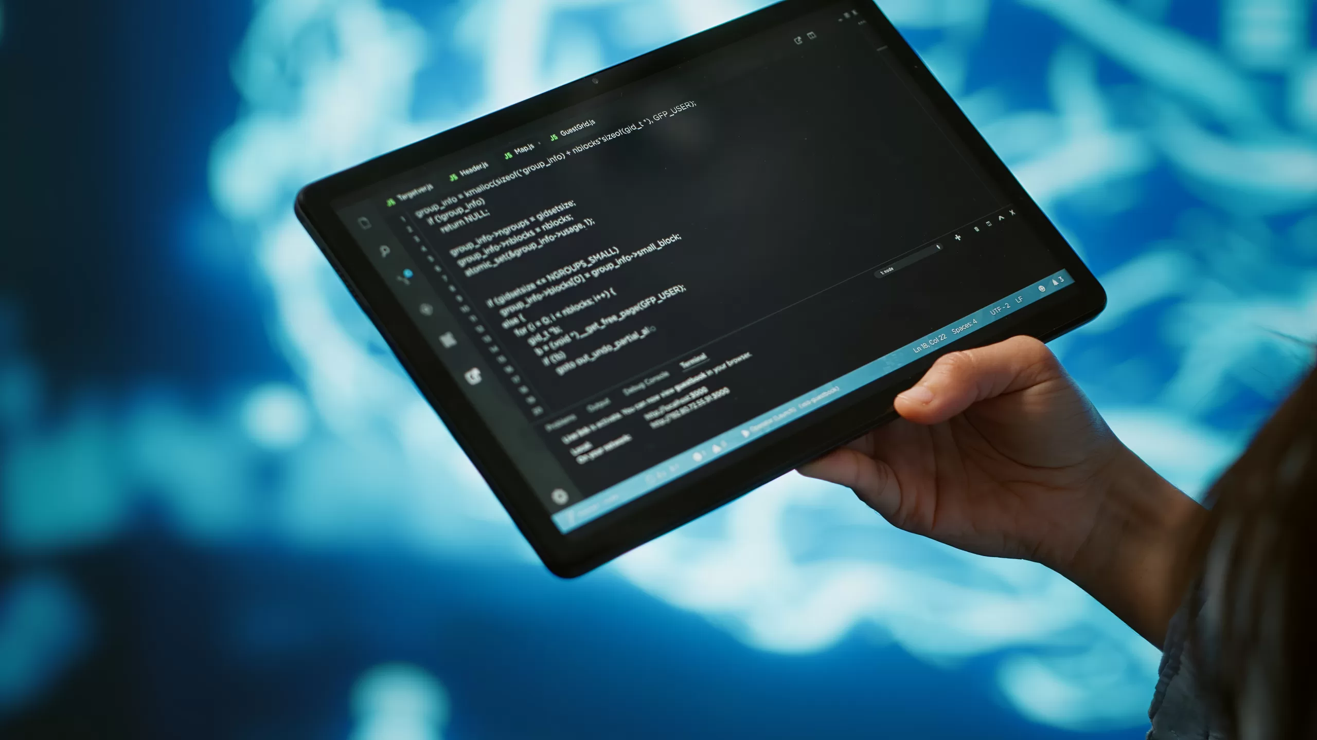 Profissional de tecnologia segurando tablet com editor de código aberto, sobre fundo azul tecnológico, representando As vantagens de low code e no code para empresas em expansão.