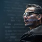 Desenvolvedor de software de óculos em perfil, concentrado, com código projetado ao fundo em ambiente escuro