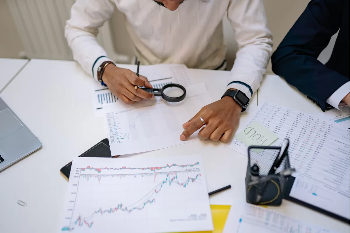 Two professionals analyzing printed charts and data on a desk during the assessment and discovery process in software projects
