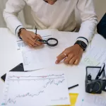 Dois profissionais analisam gráficos e dados impressos sobre uma mesa durante o processo de assessment e discovery em projetos de software