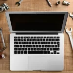 notebook com ferramentas representando sustentação AMS e manutenção contínua de sistemas corporativos