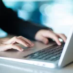 Pessoa digitando em notebook em ambiente de trabalho, representando a gestão e acompanhamento de projetos de software terceirizados