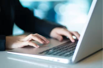 Pessoa digitando em notebook em ambiente de trabalho, representando a gestão e acompanhamento de projetos de software terceirizados