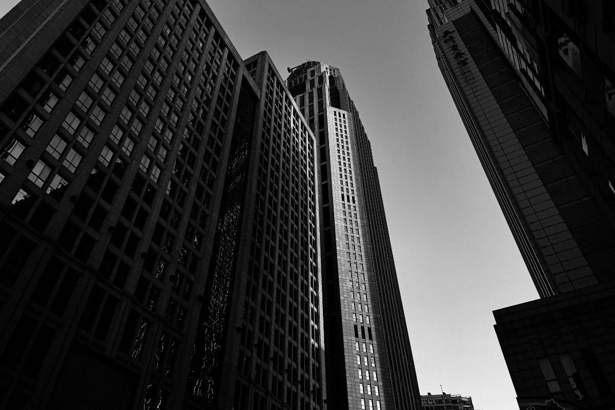 Prédios corporativos fotografados de baixo para cima em preto e branco, representando o mercado de tecnologia e software no Paraná