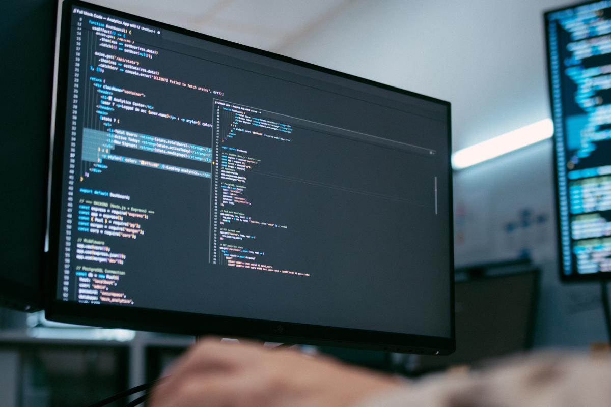 Software engineer working across multiple monitors with development code, representing the future of nearshore and AI-native engineering squads in Brazil from 2025 to 2030