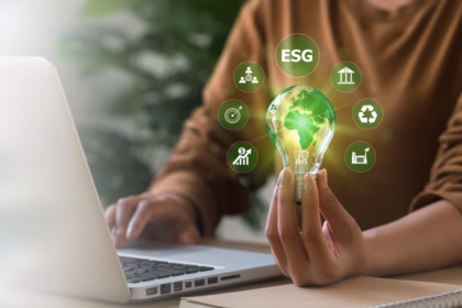 Pessoa usando notebook segura lâmpada com planeta verde e ícones de ESG, representando tecnologia, rastreabilidade e compliance no agronegócio.