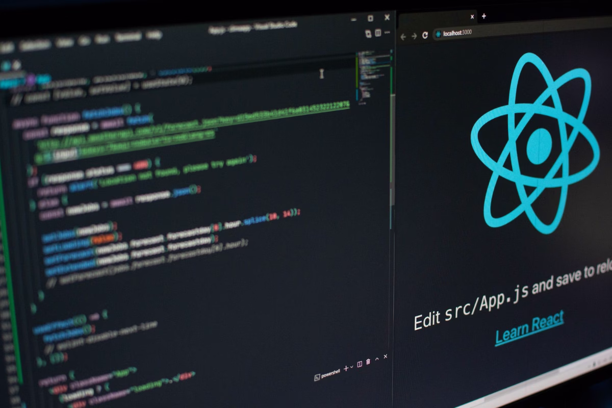 Monitor exibindo o logo do React.js e um editor de código com desenvolvimento frontend em ambiente local