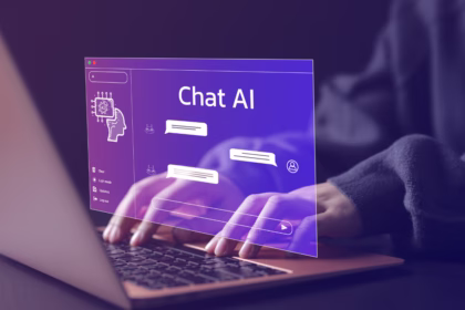 Close-up das mãos de uma pessoa digitando no teclado de um notebook. Uma interface holográfica roxa translúcida flutua sobre a tela, exibindo o texto "Chat AI" e caixas de diálogo simulando uma conversa com inteligência artificial.