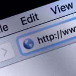 Close-up da tela de um monitor mostrando a barra de endereço de um navegador web antigo ou clássico. O cursor do mouse em formato de seta preta aponta para o campo de texto que exibe o início de uma URL com "http://www. ", evidenciando os pixels da tela e o menu superior com as opções File, Edit e View.