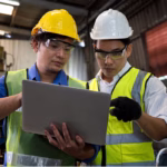 Dois trabalhadores em uma fábrica utilizando um tablet representando o que é OEE